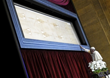 FILE PHOTO: Pope Francis touches the Shroud of Turin during a two-day pastoral visit in Turin, Italy, June 21, 2015. REUTERS/Giorgio Perottino/File Photo