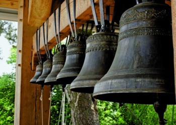 Church bells hang in a row, the bells are ringing. Church bell, several church bells in the monastery. Several metal church bells, bell ringing.